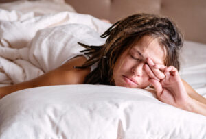Woman covering her eyes from the morning light in the bed depicting a blog post How I Fixed My Sleep Naturally: Simple Daily Habits